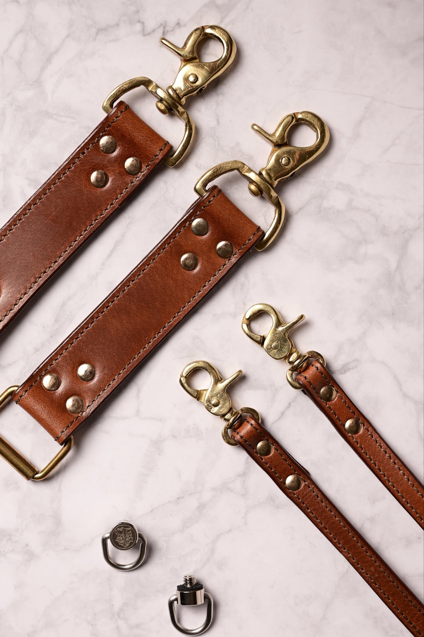 Detailaufnahme des Krützberg DUO Kameragurts aus braunem Wasserbueffelleder mit massiven Messinghaken und Nieten – handgefertigt fuer professionelle Fotograf:innen.