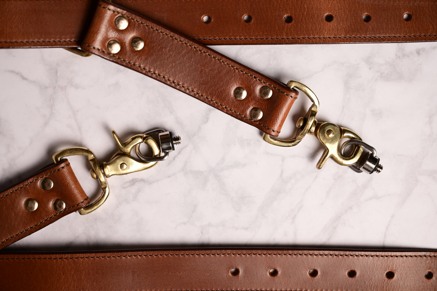 Handgefertigter Krützberg Zeithalter DUO Kameragurt aus Wasserbüffel- und Rindsleder mit Messingkarabinern und genieteter Verarbeitung auf hellem Untergrund.
